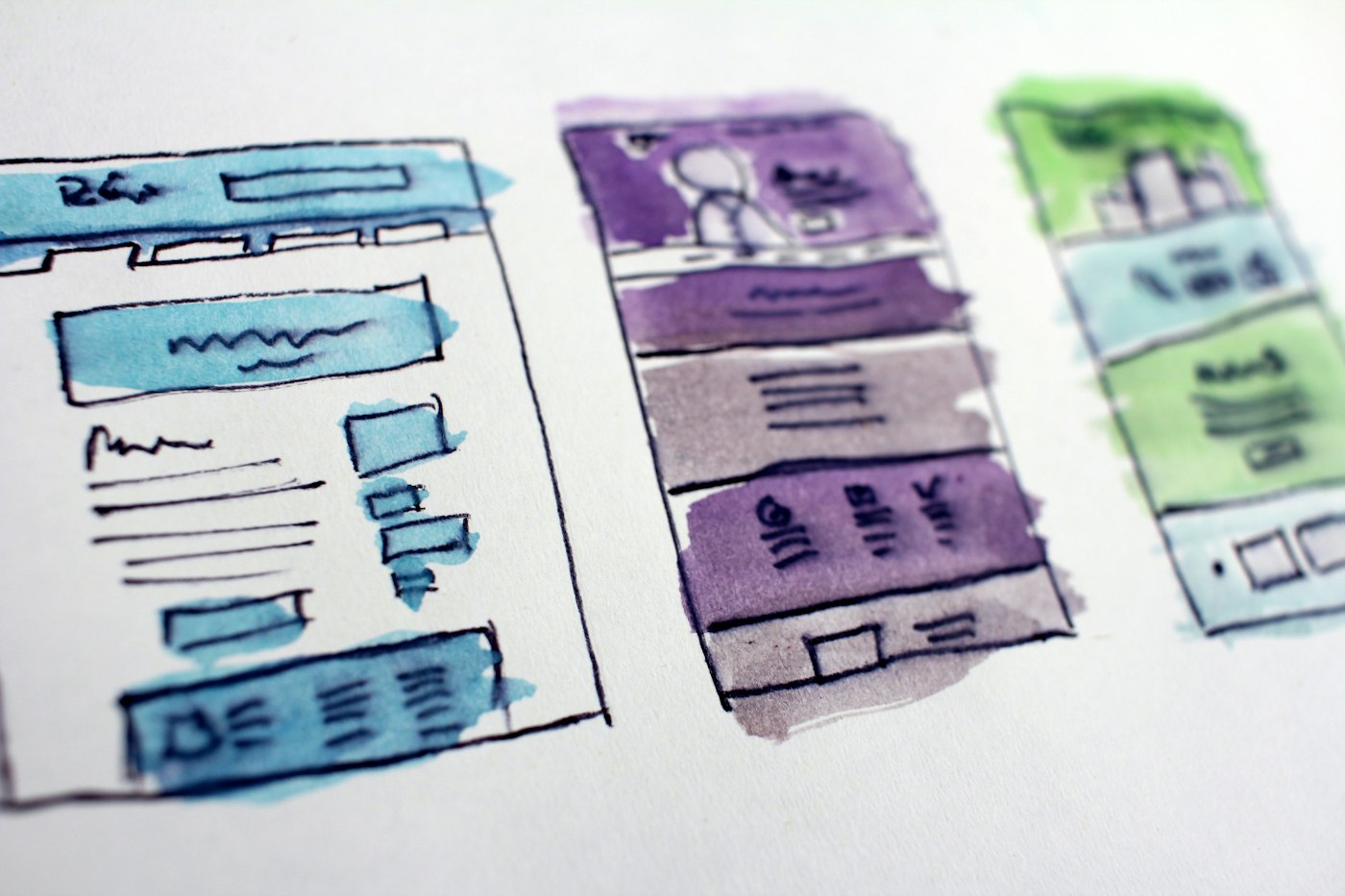 Website wireframes sketched on paper beside a laptop